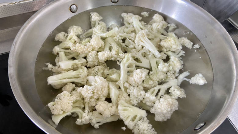 干锅菜花五花肉,坐锅烧水,水开加半茶匙食盐,几滴食用油,下菜花煮两分钟,捞出沥水备用