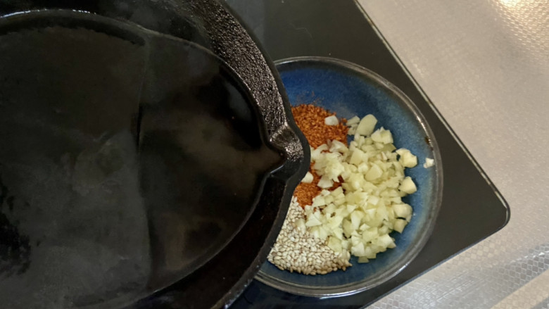 口水鸡丝,把花椒油烧到八成热,浇在辣椒粉白芝麻和一半的蒜蓉上,搅拌均匀