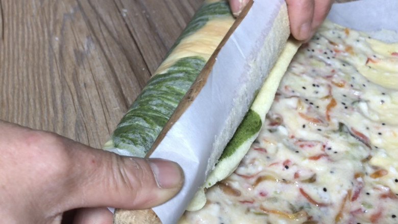 圣诞树蛋糕,凉透后铺一层馅料,借用擀面杖卷起油纸,将蛋糕推压卷成卷