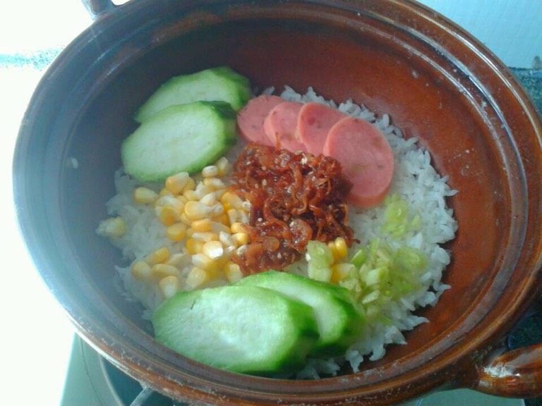 海鲜酱煲仔饭,如图。把自己喜欢吃的材料铺上去。然后盖回盖子再小火煮五分钟