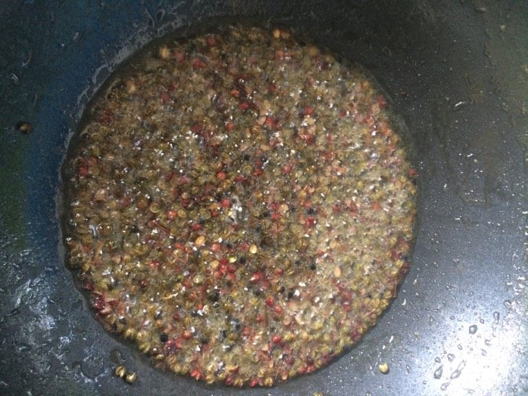 新疆美食【椒麻鸡】,如图锅烧热倒油,油温四成热时下入花椒,慢慢焙出香味