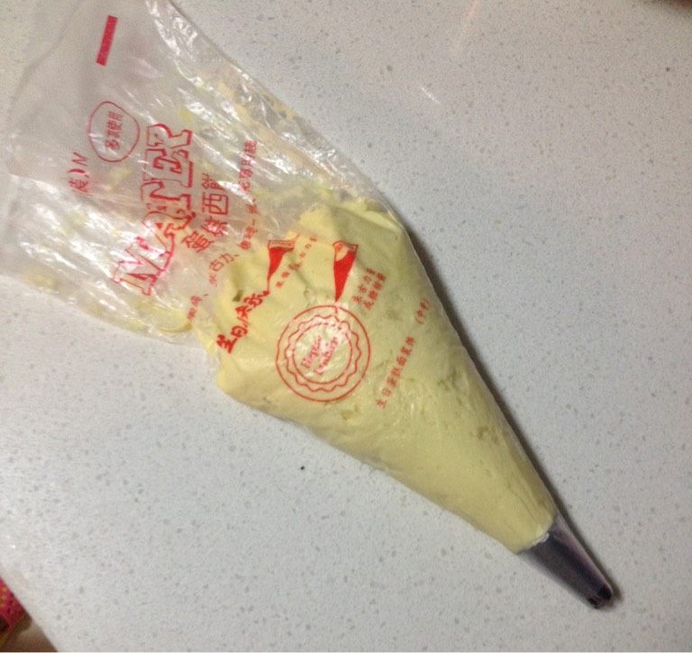 黄油小曲奇,将面糊装入安好了尖齿菊花嘴的裱花袋中,烤盘铺上烘焙专用纸,将花嘴离烤盘距离一厘米高度以垂直角度挤出小花形状