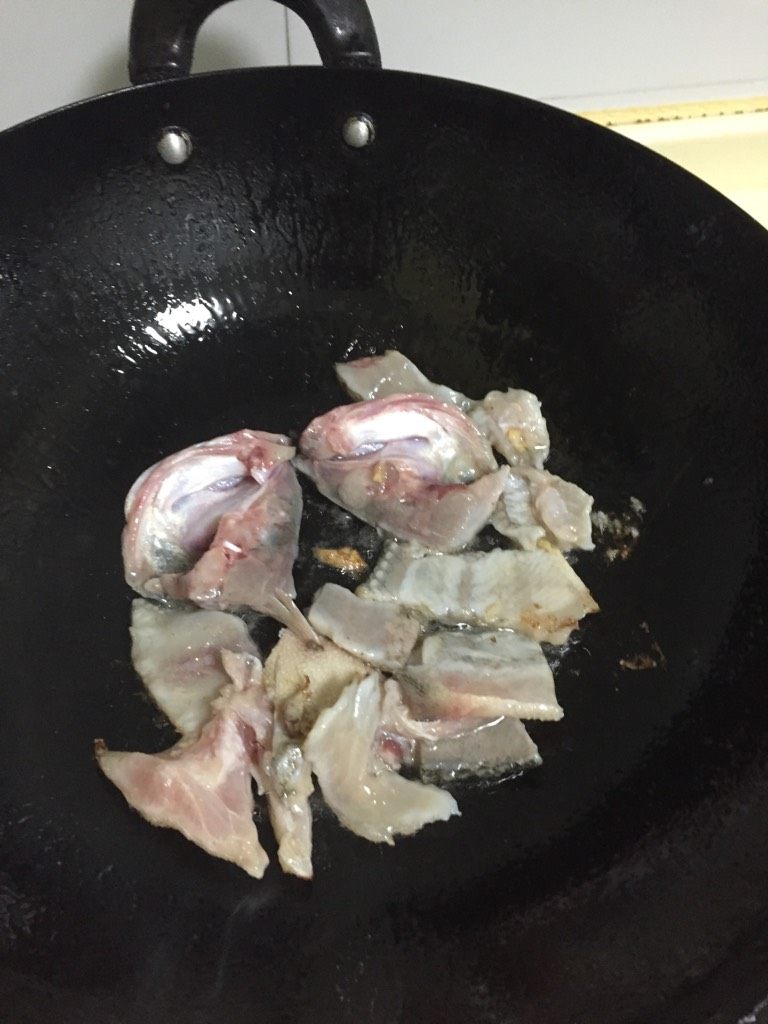 酸菜鱼刀削面片,锅烧热加入底油,放入片下的鱼骨进行煸炒后盛出备用
