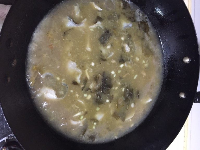 酸菜鱼刀削面片,将里面的鱼骨捞出,放入腌制好的鱼片,轻轻的搅动一下