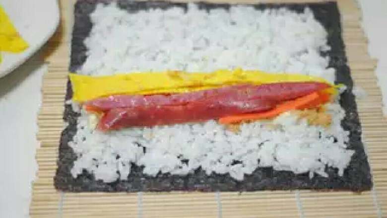 寿司,铺平后把<a style='color:red;display:inline-block;' href='/shicai/ 54'>黄瓜</a>，<a style='color:red;display:inline-block;' href='/shicai/ 437'>火腿肠</a>，<a style='color:red;display:inline-block;' href='/shicai/ 9'>鸡蛋</a>放在最前面