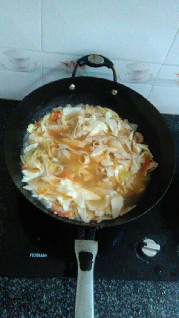 羊肉烩刀削面,锅里放油，炒羊肉、姜片、辣椒，蒜泥，白菜，番茄，翻炒均匀兑入原汤，大火烧开，加入盐，胡椒粉，然后放入面条