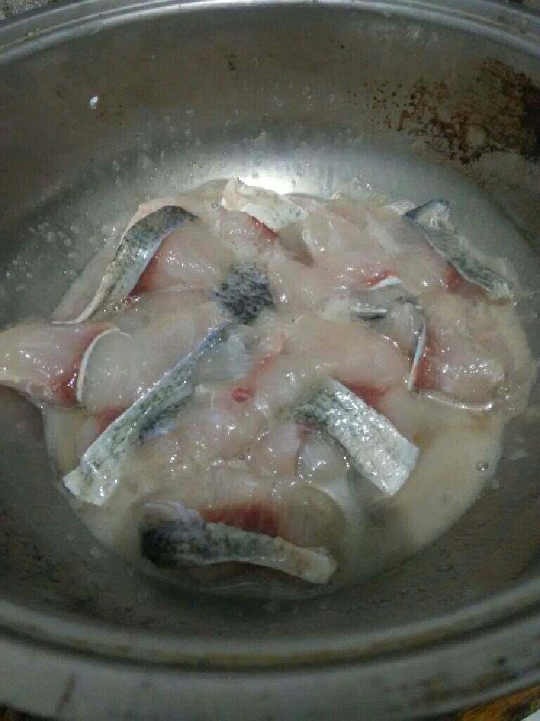 川味酸菜鱼,鱼洗净，切下鱼头，顺着中间的大骨开始取鱼肉，鱼头劈对开，鱼骨切小块，片下鱼腹的大骨，切成条，然后开始片鱼，大概5毫米左右的厚度，从鱼尾开始，你要是怕小了，可以一片隔一片，就是第一刀片下去到皮，第二刀片下去切断，这图是我腌好剩下的一半，因为老公还没回来，所以我只煮了一半