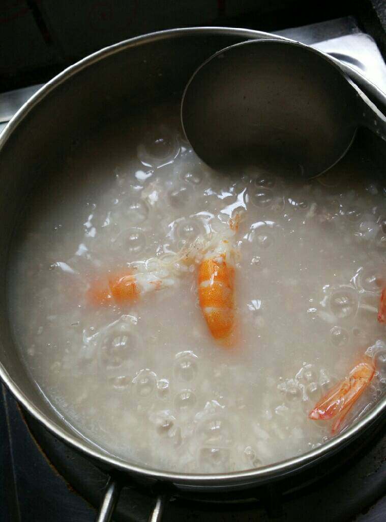 鲜虾瘦肉粥,取锅舀入适量白粥煮开,加入瘦肉泥用锅勺弄散和粥混合在一起,加入虾煮开
