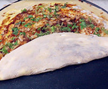 杂粮煎饼,撒上香菜、榨菜碎,将饼翻起三分之一