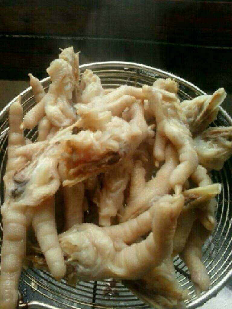 爆炒鸡爪,等锅里的水变成白色的就差不多了,不要把鸡爪煮得太烂,等会儿炒得时候会沾锅、用漏筛捞起鸡爪,汤和桂皮就不要了