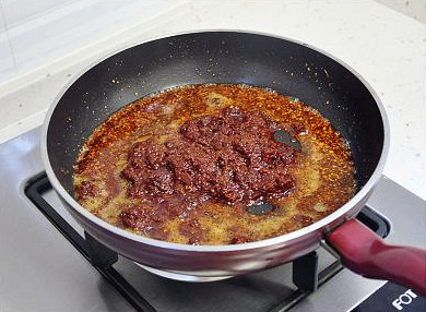 麻辣牛肉,当油的颜色也变红了，就可以倒入素食佐餐酱，小火炒至有酱香味冒出。