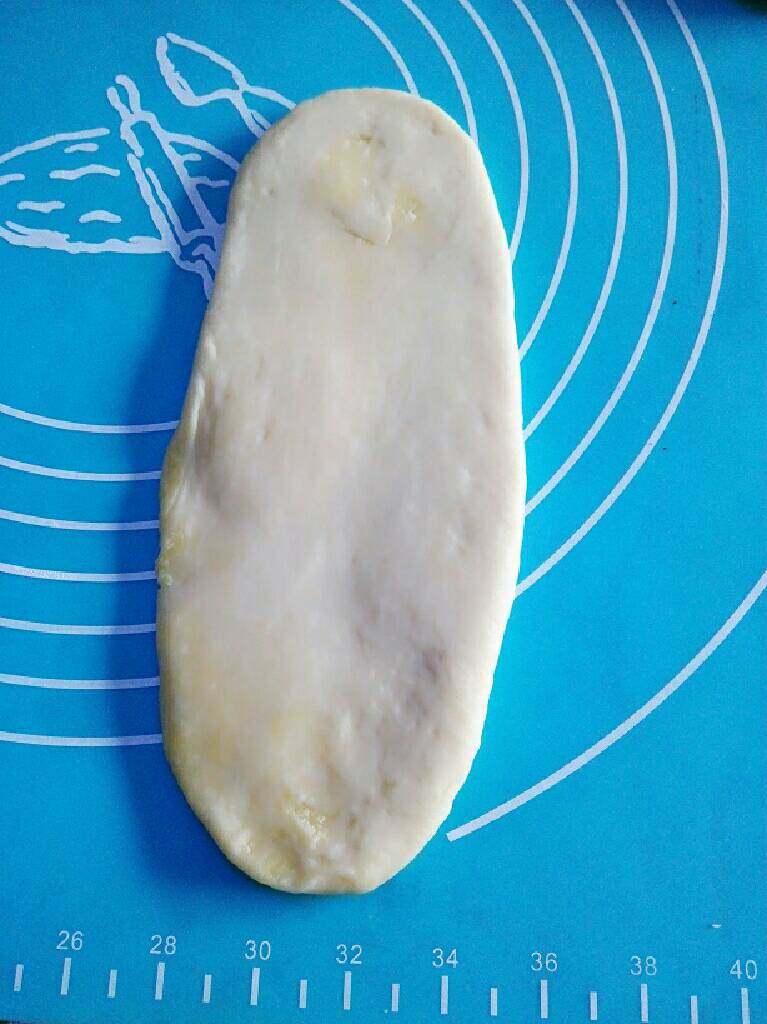 奶香椰蓉面包,用擀面棒将装有椰蓉的面团擀成一个扁的长的椭圆形(须小心地擀,不要将椰蓉馅儿擀出来)。