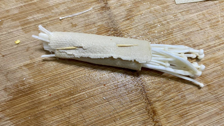 金针菇豆皮卷,取一些金针菇,用豆皮卷起,牙签固定