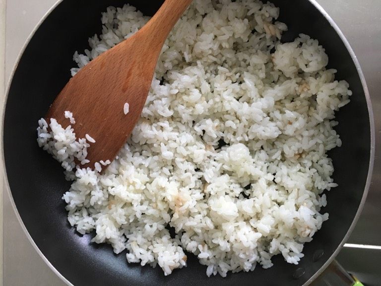 葱花蛋炒饭,油微热后倒入米饭,炒热、炒软。