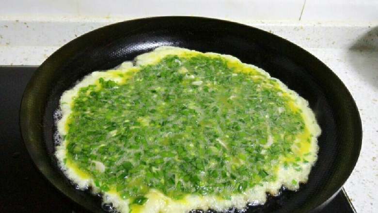 韭菜鸡蛋饼,锅里倒入适量油,烧热后慢慢倒入韭菜蛋液,并移动锅使其成为一个圆形。