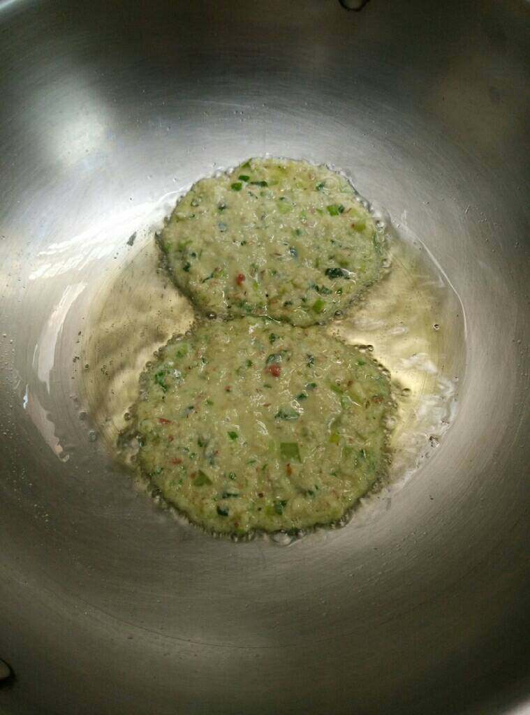 芹菜豆渣饼(营养早餐),热锅入油,油大约七成热舀一勺豆渣糊摊平成圆形,能定型即可。