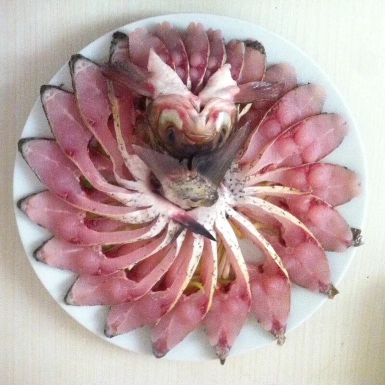 孔雀开屏鱼,腌制好的武昌鱼在铺好葱花姜丝的盘子上一片一片鱼肉分开,排出孔雀开屏的造型,鱼头从下颌处劈开,不要断,立于鱼身,尾巴稍微处理挨着鱼头码好