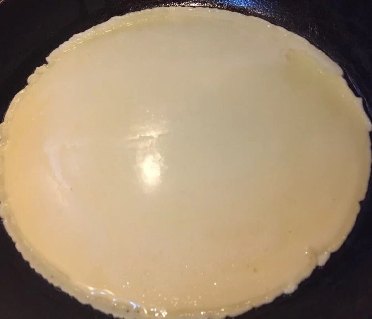 培根生菜卷,如图锅中刷油,油热倒入面糊,快速晃动平底锅使其成为一个圆饼。
