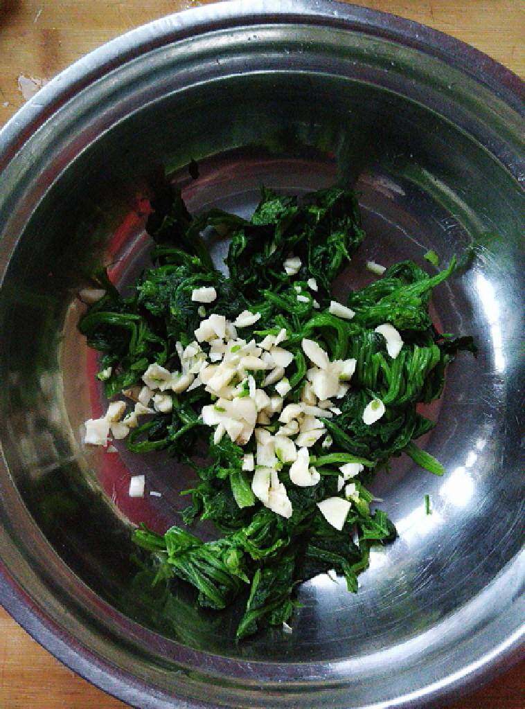 凉拌菠菜花生米,菠菜装到大容器里,蒜瓣剁碎。