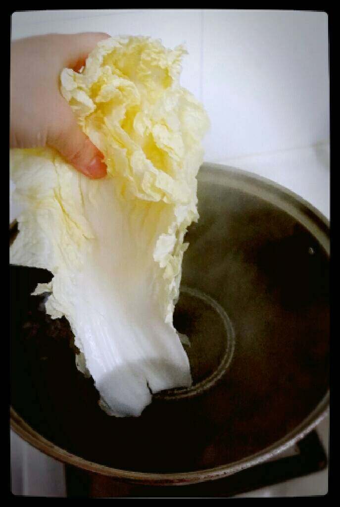 简单快速自制酸白菜,转小火,保持开的程度就可以了,然后把白菜从杆的位置先放进锅里略煮2~3分钟,然后再让整片白菜都浸没在锅里。
