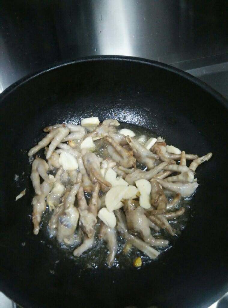 香辣凤爪,油烧热放入鸡爪、<a style='color:red;display:inline-block;' href='/shicai/ 37'>姜</a>、蒜爆至鸡爪颜色焦黄