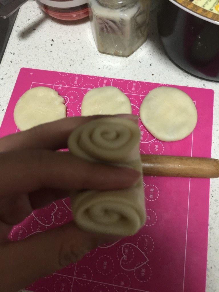 蛋黄酥,将松弛好的面卷用拇指在中间压一下,然后将卷对夹起来。将对夹方向朝上用手按扁,再擀成圆饼状。