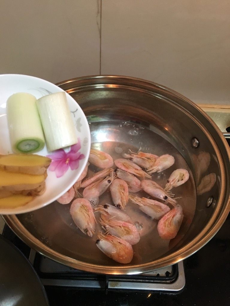 鲜酥北极虾,锅中烧热水,水开后下入部分解冻后的北极虾、再放入葱段和姜片、3~5分钟后捞起、