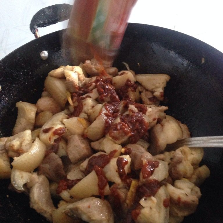 豆腐乳炖猪脚,如图大概炒10到15分钟左右关火,因为这里关火是有原因的,把准备好的豆腐乳美味香酱倒进去翻炒均匀,再次开火,要不停的翻炒这里,把酱料均匀的炒裹在肉上,这个步骤也要炒久点