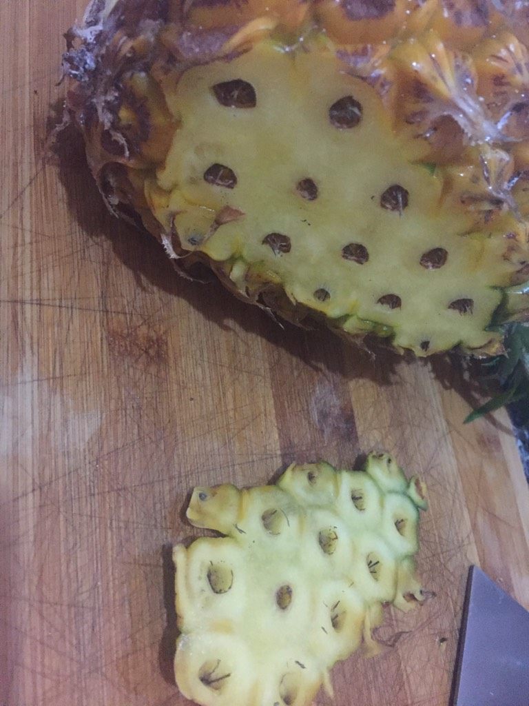 菠萝炒饭,如图从菠萝颜色比较偏绿色的一面切一小块不要太厚,为了让菠萝立的更牢固