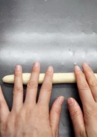 香蒜面包结,取一份松驰好的面坯,再将揉搓成长条。