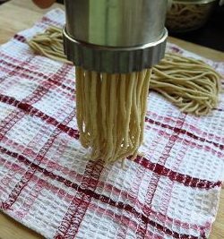 麻油炒莜面,用压面器分别将三个小面团压成饸饹面条,压出的面条要放在一块比较干些的蒸布上,防止蒸的时候过多的水份把面条打湿。