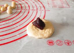狮子肉松小餐包,取一个面团,用擀面杖擀成圆片状,放入适量<a style='color:red;display:inline-block;' href='/shicai/ 4729'>豆沙馅</a>