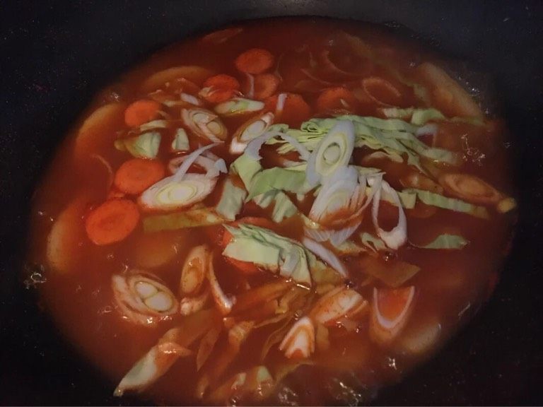 辣炒年糕,如图加入胡萝卜,圆白菜,煮至汤汁浓稠,(不断的翻动年糕避免糊锅)撒入适量盐翻炒均匀