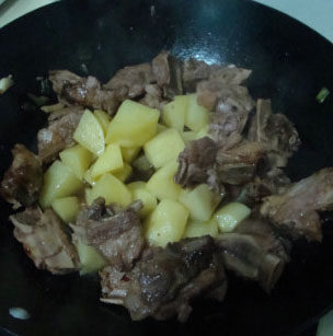 压锅酱烧土豆排骨,土豆倒入炖锅中，放上压好的排骨和排骨汤，加适量盐炖至软糯