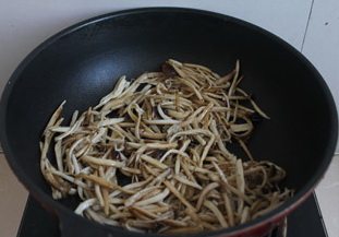 茶树菇炒茼蒿,放入茶树菇慢慢煸炒,炒到茶树菇有点脱水,呈现焦黄色即可。