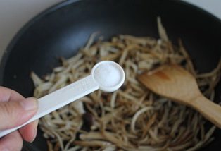 茶树菇炒茼蒿,放入一小勺盐调味。