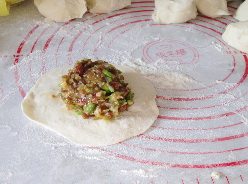 猪肉芹菜大包子,取一小面团,擀成中间厚,外围薄的面饼。放上馅料。