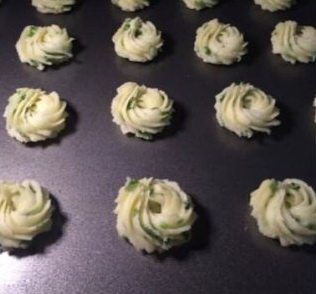 香葱曲奇,用小号菊花嘴挤出大小一致的花纹,入预热好的烤箱烘烤至表面金黄,出炉后立即放在晾网上晾凉密封