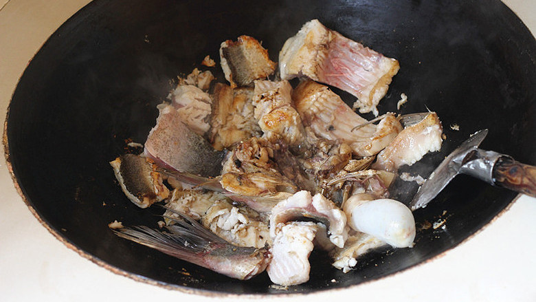 灶头家常红烧鱼,煎一回，鱼肉变色微黄后把鱼块翻身。