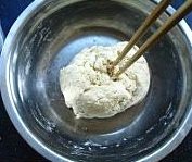 霍州干面饸饹,面团用筷子搅拌成团状后,手沾剩余的水,手一边沾水一边揉面团。