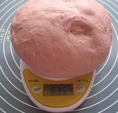 紫薯红豆沙吐司,发酵好的面团轻轻揉至排尽气体,上称。