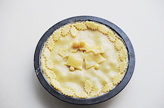 圣诞平安派(苹果派),再将剩余的派皮擀成3mm左右厚,铺在派馅上,用刮板刮掉多余的派皮,表面刷一层蛋黄液,将多余的派皮刻成叶子状、铃铛等圣诞素材的装饰饼皮,贴在派顶部,烤箱预热200℃,中层烘烤20-25分钟,表面呈棕黄即可出炉,出炉后室温冷却切块享用