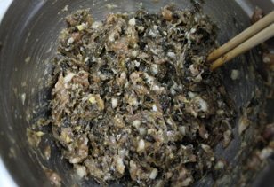 梅干菜包子,炒好的梅干菜放入肉馅里,搅拌上劲。