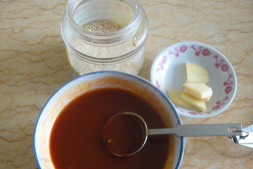 红油鱿鱼,碗中加入一汤匙豆瓣酱,4汤水清水,2汤匙鲜酱油,和一茶匙白糖拌匀,准备<a style='color:red;display:inline-block;' href='/shicai/ 2800'>生姜</a>片和白芝麻