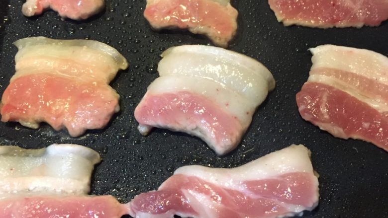 铁板五花肉,如图铁板预热，刷适量食用油，放入五花肉用铲子轻轻按压使其均匀受热烤至一面金黄