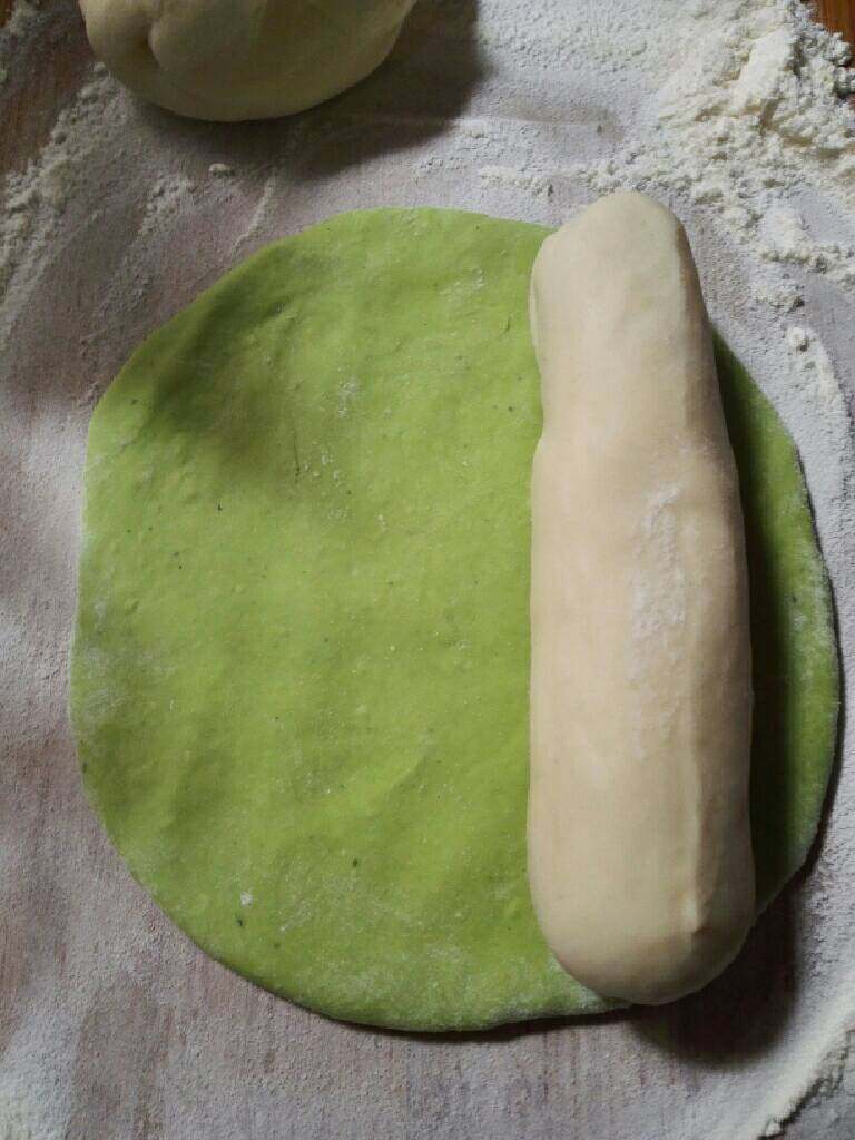 翡翠饺子,取适量菠菜面团擀成面皮,再放上撮成圆条白色面团。