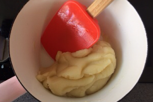 巧克力奶油夹心泡芙,关火后立即加入过筛的中筋面粉搅拌均匀,开小火继续边加热边翻拌,使多余水份蒸发掉,锅底出现一层薄膜时离火