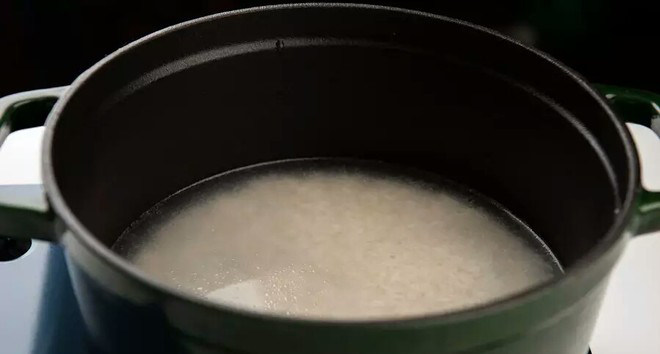 铸铁锅版皮蛋瘦肉粥,在珐琅锅内滴入一滴油,并依据个人喜好添加适量的水(水量决定粥的稀稠程度),同时将浸泡好的大米倒入锅中,盖上锅盖中火烧开