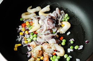 芝士焗海鲜饭,平底不粘锅加少许油,开小火,加入海鲜和蔬菜,转中火炒至海鲜颜色开始变白;