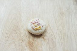 面包超人挤挤面包,发酵好的面团取出排气,分成16等份,取一份滚圆摁扁,中间放入馅料并包起来,收口处掐紧;